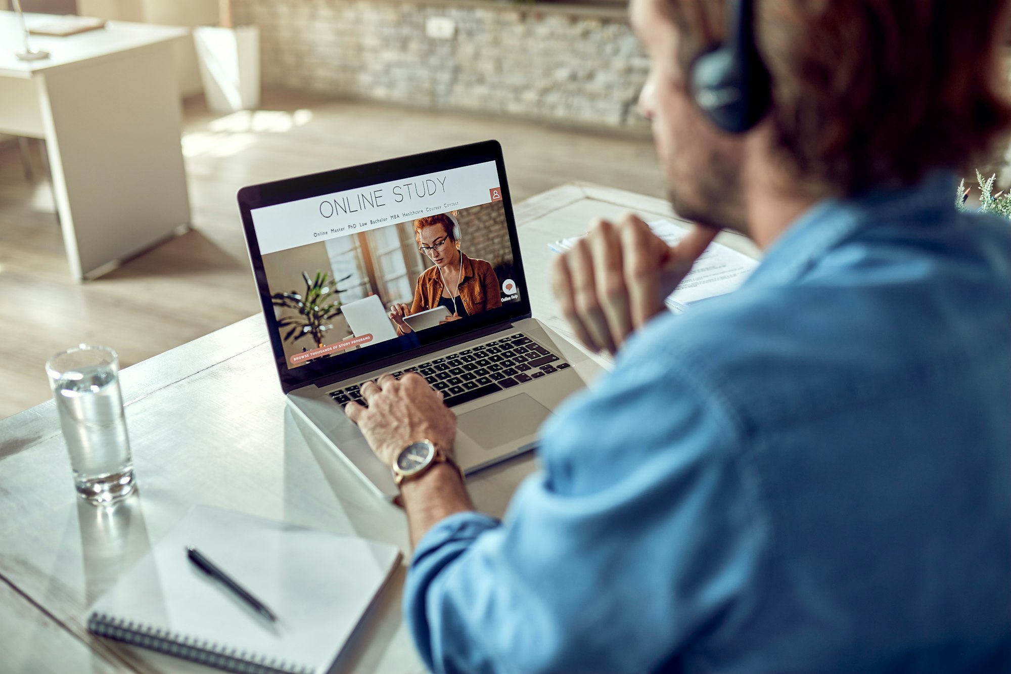 Unrecognizable man choosing online study program while using laptop.